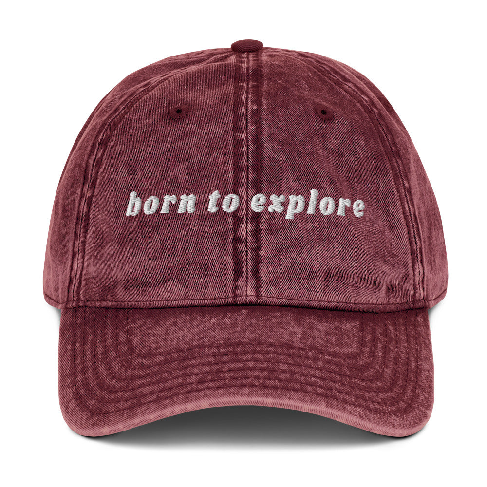 Maroon cap with 'born to explore' text on a white background