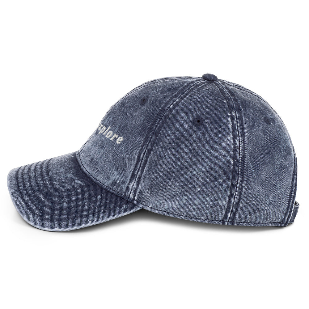 Blue denim cap with 'born to Explore' embroidery on a white background