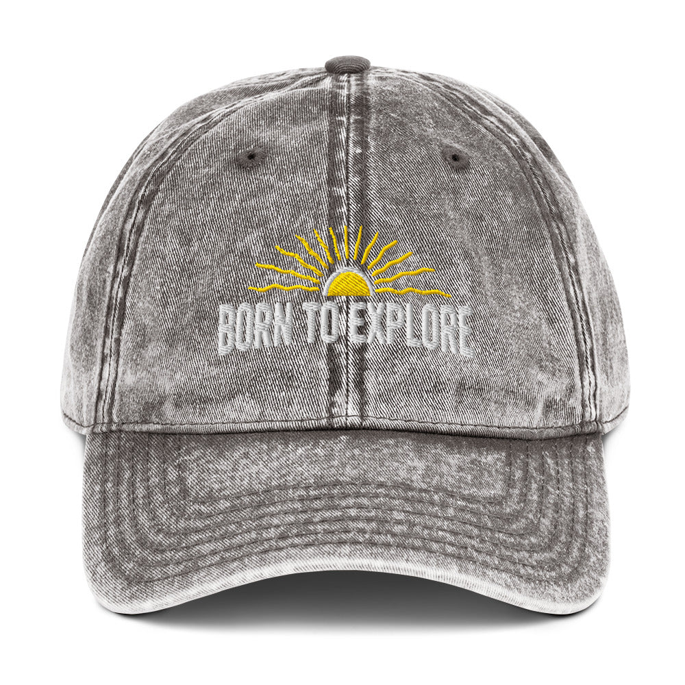 Light gray denim cap with 'Born to Explore' text and sun graphic on a white background