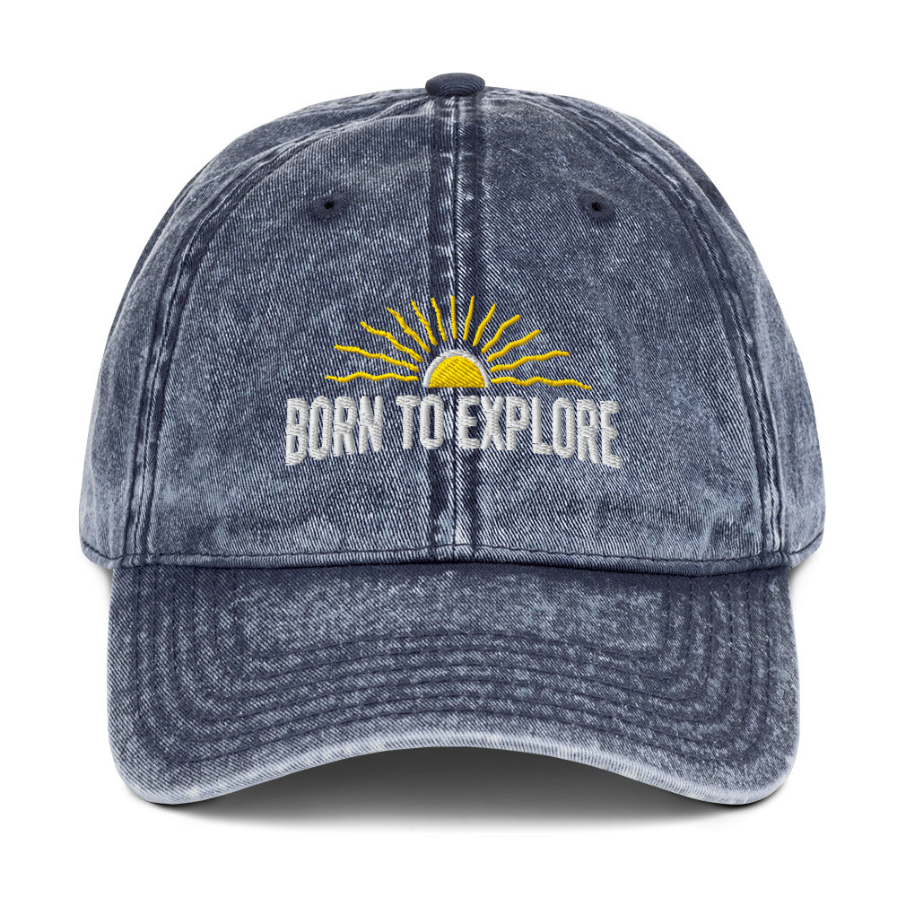 Blue denim cap with 'Born to Explore' text and sun graphic on a white background