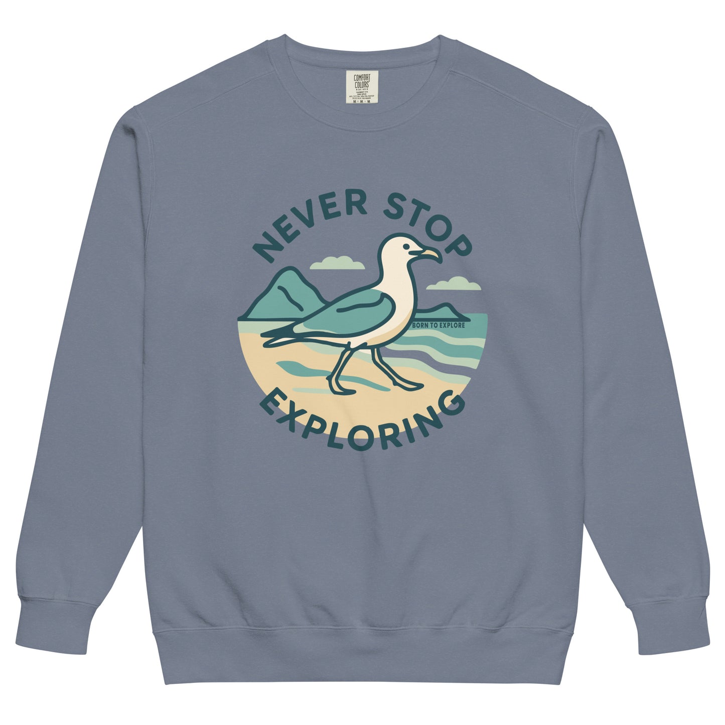 Gray/blue sweatshirt with a seagull, beach and ocean graphic and 'Never Stop Exploring' text on a white background