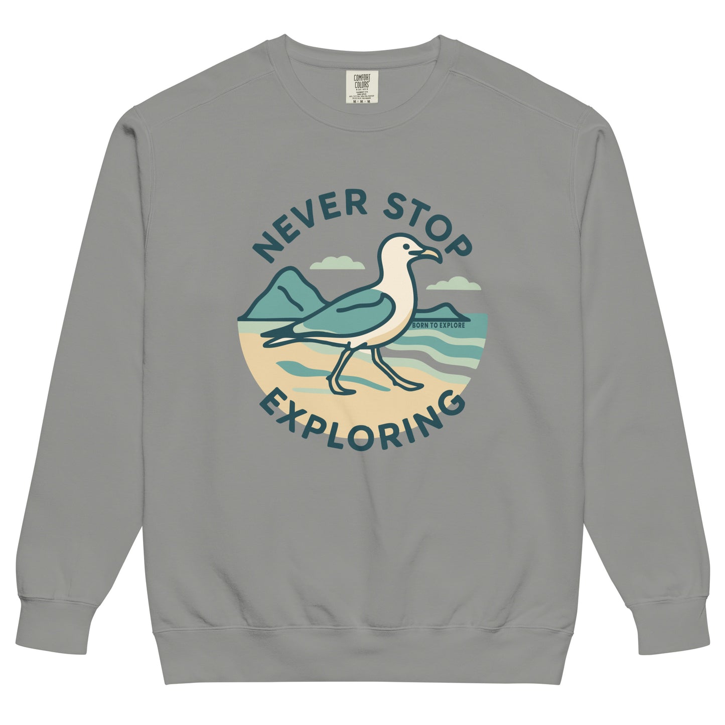 Gray sweatshirt with a seagull, beach and ocean graphic and 'Never Stop Exploring' text on a white background