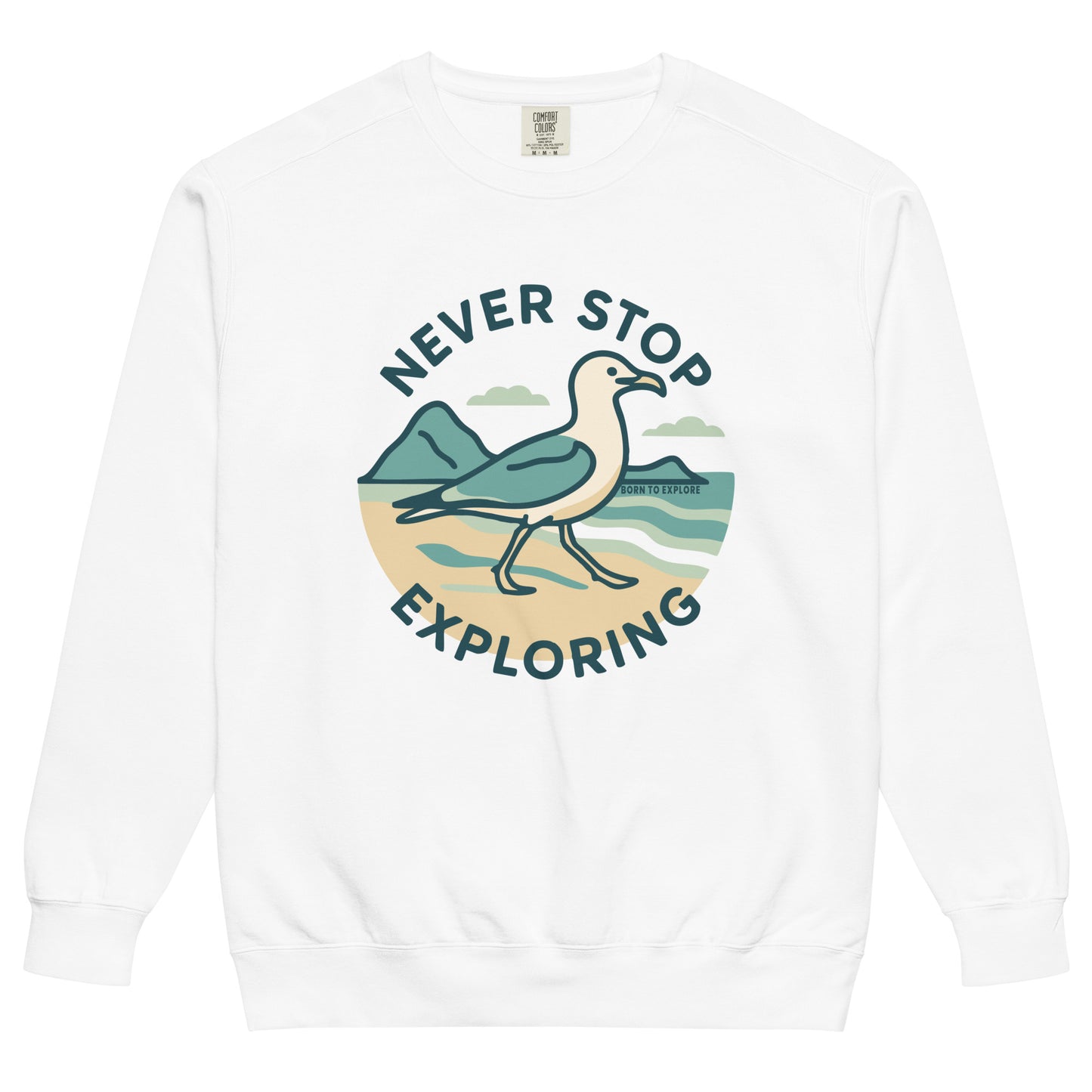 White sweatshirt with a seagull, beach and ocean graphic and 'Never Stop Exploring' text on a white background