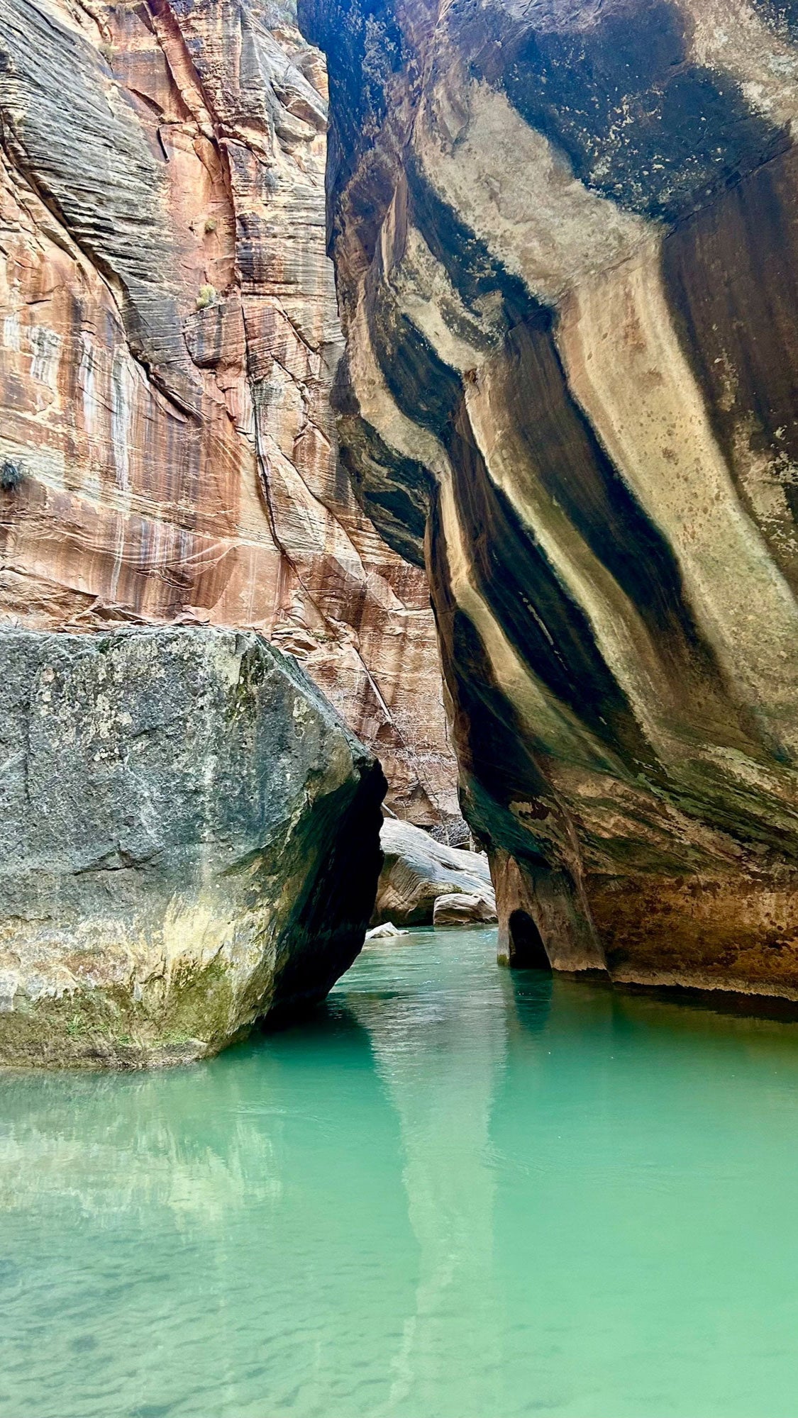 Canyon with water flowing through it, surrounded by layered rock formations.