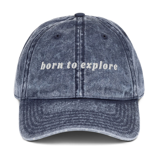 Blue denim cap with 'born to explore' text on a white background