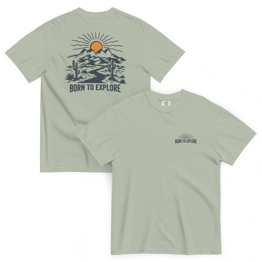 Light green t shirt with nature themed graphic design, sun, mountain, cacti and dirt trail with the text 'born to explore'