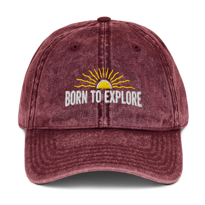 Maroon cap with 'Born to Explore' text and sun graphic on a white background