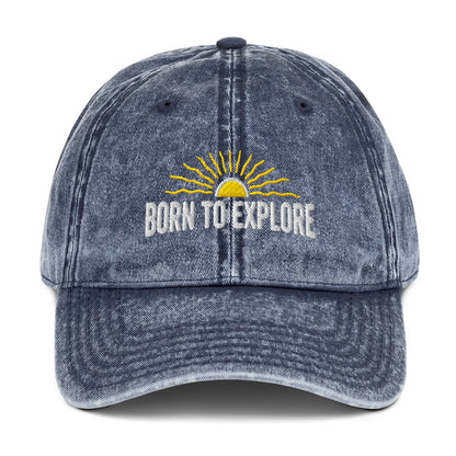 Blue denim cap with 'Born to Explore' text and sun graphic on a white background