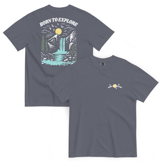 Denim colored t-shirt with nature-themed design, trees, mountain, waterfall, birds flying near sun and 'Born to Explore' text on a white background